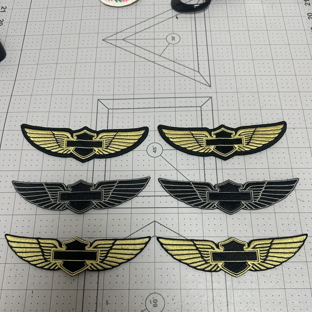 Custom embroidered wing badges in gold on black twill