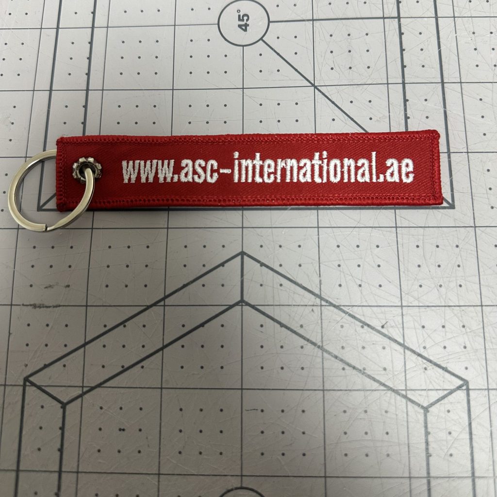 Custom embroidered keychain tag in red with white text