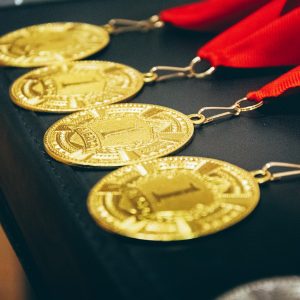 Row of custom struck gold award medals on red ribbons